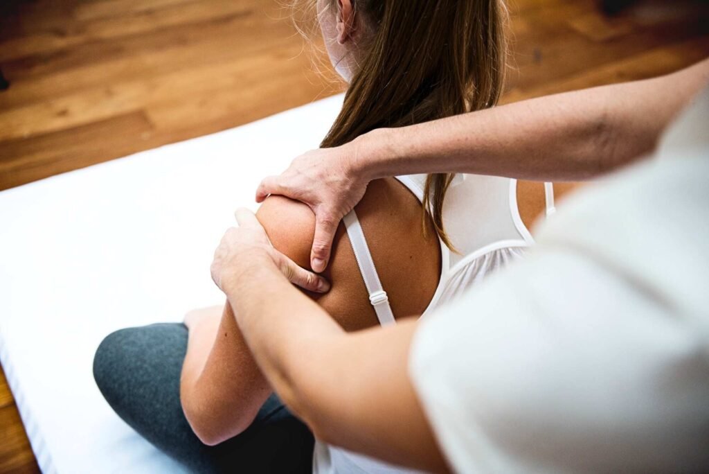 Chiropractor applying myofascial release technique to a patient's shoulder to relieve tension and improve mobility.