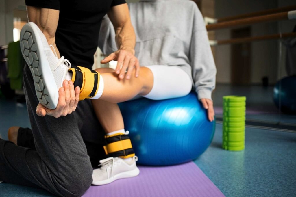 Physical therapist guiding a patient through lower limb rehabilitation using resistance training and a stability ball.